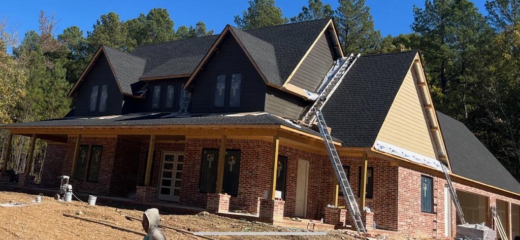 A work in progress home. It is in the final stages and shows the brick base and black roof.