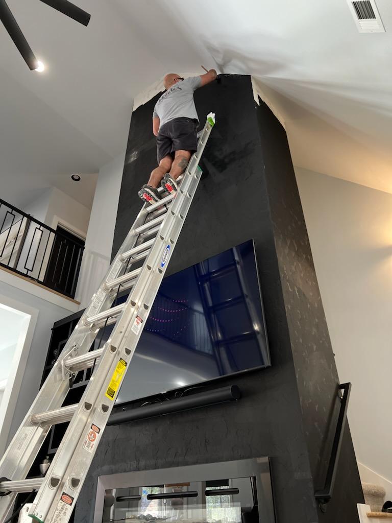 A picture of the owner at the top of the ladder finsihing a home