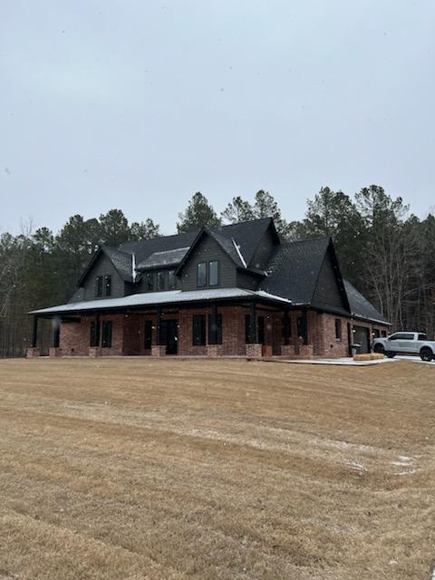 The founders finished home and personal project. A brick home with a black rood with a truck parked out front